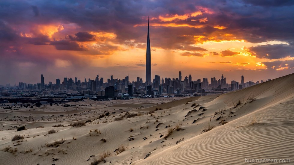 Lo skyline di una metropoli mediorientale al tramonto, tra grattacieli e deserto.