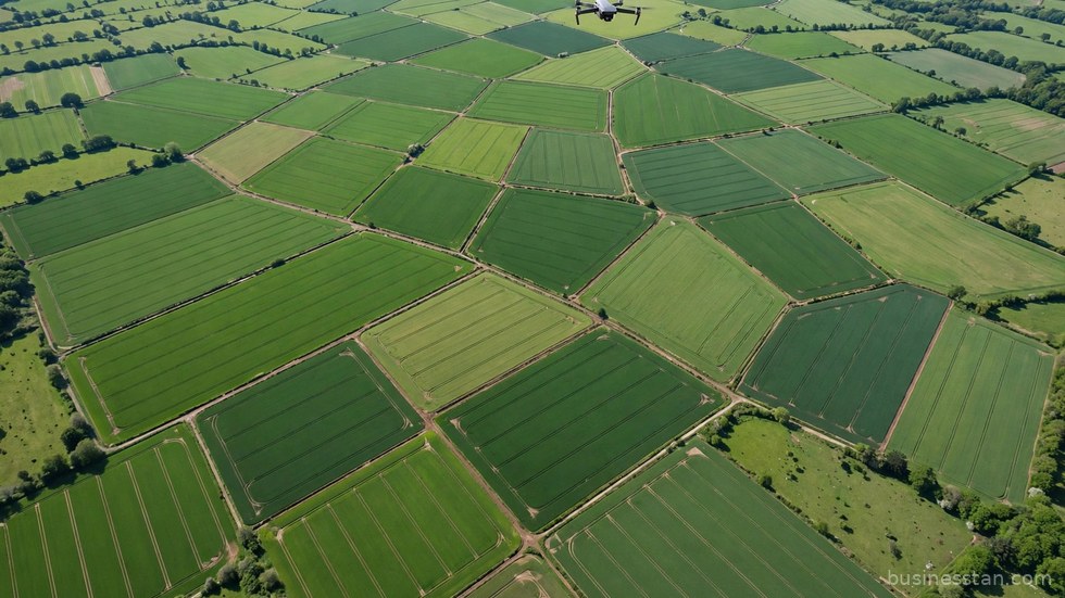 Drone in volo sopra un campo agricolo verde per il monitoraggio delle colture.